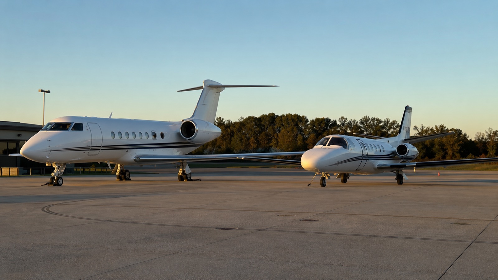 Two business jets parked side by side on the ramp